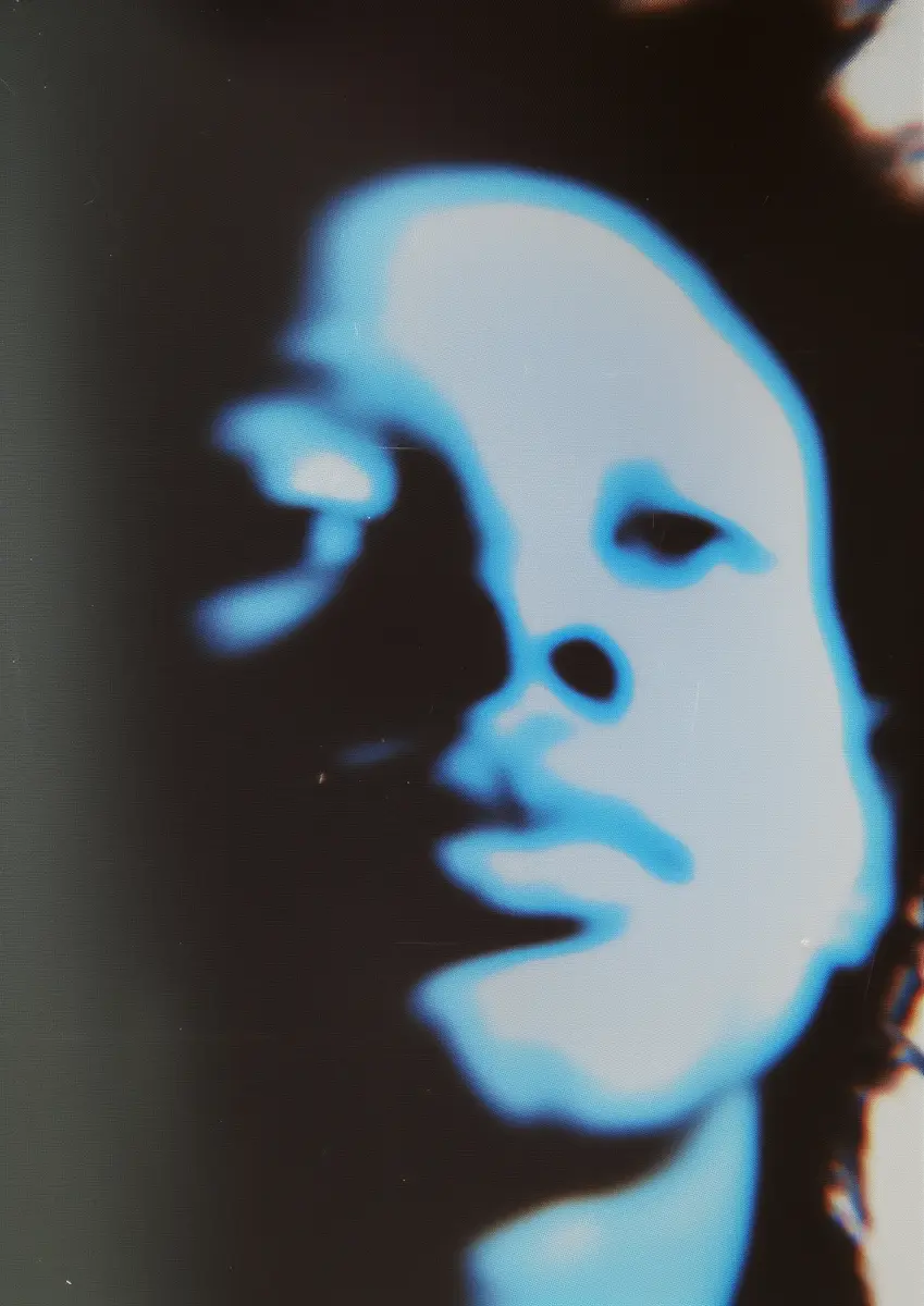 Abstract close-up of a person's face with blue glow and dark shadows, highlighting nose, lips, and eyes.